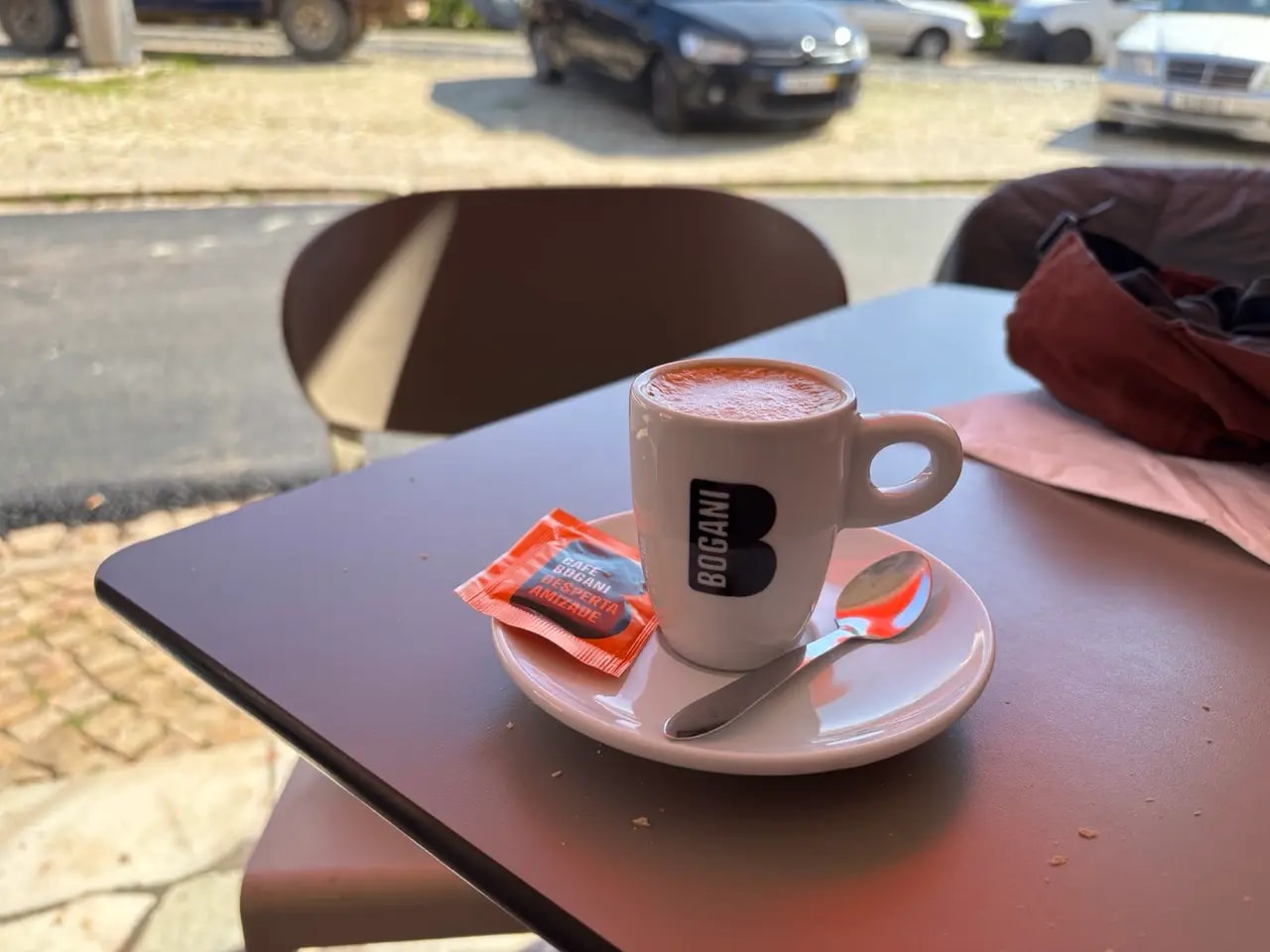 Espresso in a white cup on an outdoor café table with a sugar packet