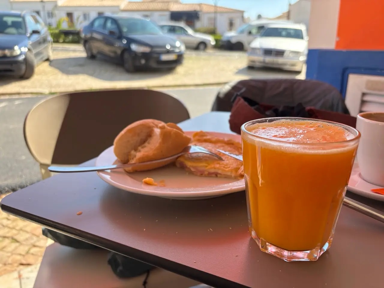 Glass of freshly squeezed orange juice with bread, omelette and espresso on an outdoor café table