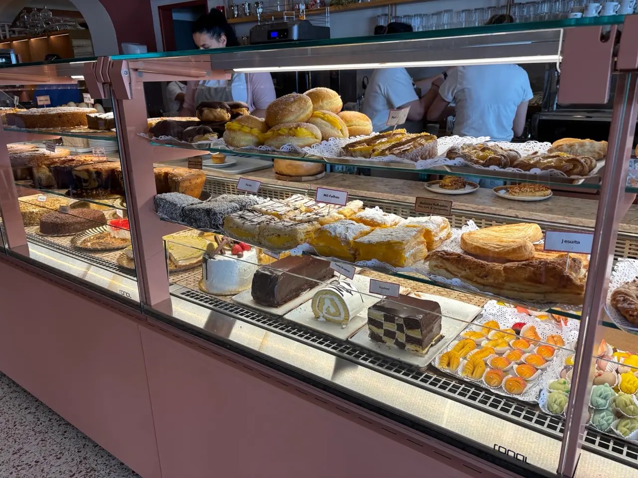 Glass display case filled with Portuguese cakes and pastries in a pastelaria